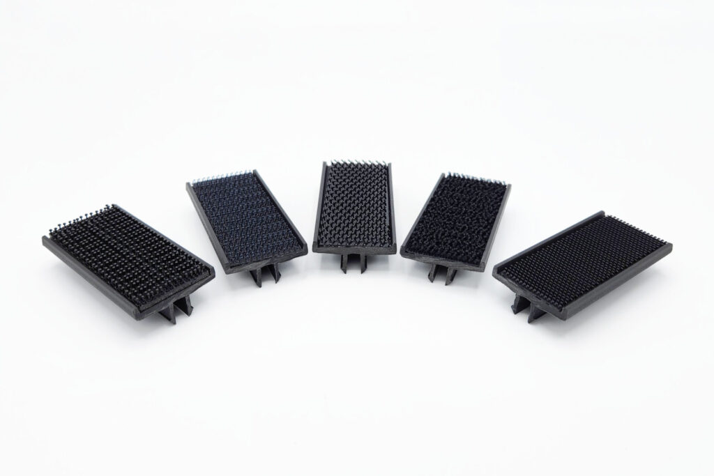 Five black hook-style fastener pads, each with textured bristles and small clip tabs underneath.