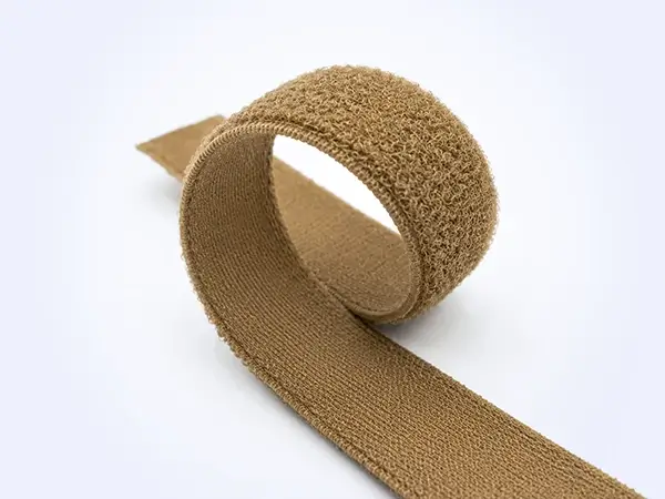 Cinta elástica de bucle HALCO color marrón coyote curvada para mostrar su construcción flexible.