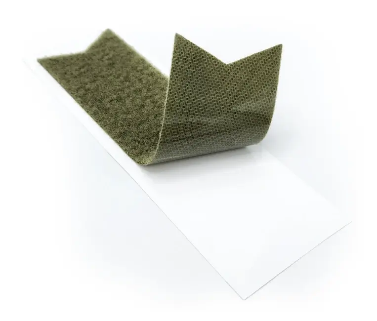 Tira adhesiva de velcro de color verde oliva parcialmente despegada de su revestimiento blanco.